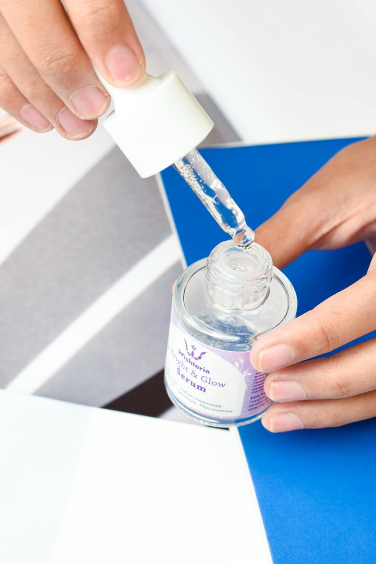 Hands using a dropper to apply serum from a glass bottle, ideal for skincare and beauty concepts.